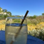 Ein Glas mit einem eisgekühlten Getränk und Strohhalm steht auf einem Holztisch.